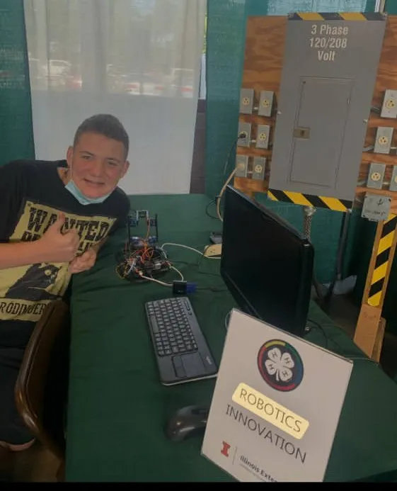 Bryce presenting the custom robotic arm at the Illinois Extension Robotics Innovation table